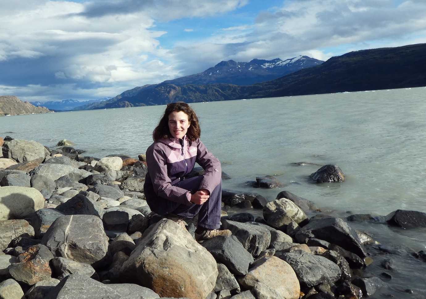 me sat on shore of lake grey in sunshine Torres del Paine W trek